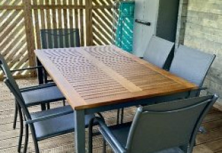 Buiten eettafel en stoelen op houten terras bij Chalet op Camping La Grande Véyière, Frankrijk.