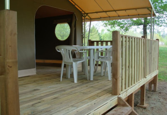 Terrazza in legno con tavolo e sedie di plastica davanti a una tenda safari al Lodge «Canada Classic», Campeggio La Grande Véyière, Francia.