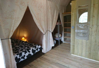 Interno del Lodge Canada Comfort, tenda safari al campeggio La Grande Véyière in Francia, con letti accoglienti.