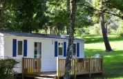 Mobile Home Comfort at Campsite La Grande Véyière in France, surrounded by green grass and tall trees.