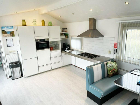 Moderne køkken i Comfort 4 personen MIVA-hytte på De Woudhoeve, Holland, med hjørnesofa og lyst interiør.