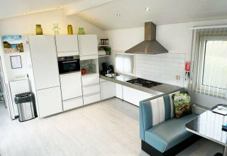 Moderne køkken i Comfort 4 personen MIVA-hytte på De Woudhoeve, Holland, med hjørnesofa og lyst interiør.