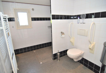 Baño accesible con inodoro suspendido, barras de apoyo y azulejos en blanco y negro en De Woudhoeve.