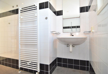 Baño con azulejos en blanco y negro, lavabo, espejo y radiador toallero en Comfort 4 personen MIVA, De Woudhoeve.