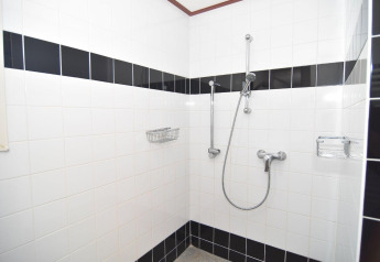 Ducha accesible en la cabaña 'Comfort 4 personen MIVA' de De Woudhoeve, Países Bajos, paredes con azulejos.