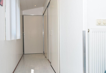Pasillo luminoso en la cabaña Comfort 4 personen MIVA de De Woudhoeve, Países Bajos, con paredes blancas.