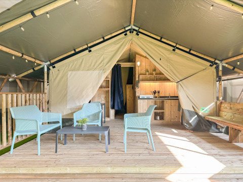 Tienda safari con suelo de madera, área de asientos moderna y cocina con instalaciones sanitarias privadas.
