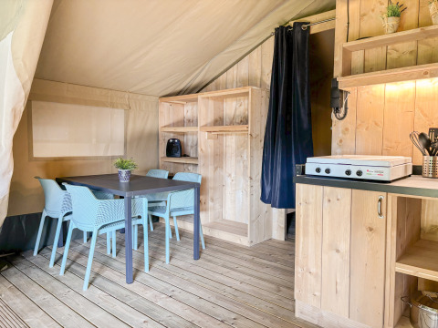 Innenraum eines Safari-Zeltes auf dem Campingplatz Hunze Bulten in den Niederlanden mit Essecke und Küche.