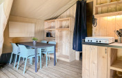 Indretning af safaritelten på Campsite Hunze Bulten i Holland med spisebord, stole og køkkenområde.