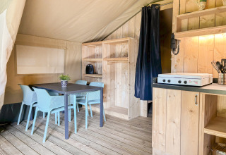 Indretning af safaritelten på Campsite Hunze Bulten i Holland med spisebord, stole og køkkenområde.