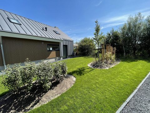 Well-kept lawn and garden beside a modern lodge, Duinvilla, at EuroParcs Texel in the Netherlands.