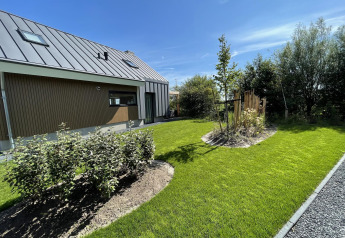 Gepflegter Garten und Rasen neben einer modernen Lodge, Duinvilla, im EuroParcs Texel, Niederlande.