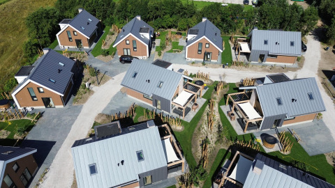 Aerial view of Duinvilla Wellness lodge with modern cabins, green lawns, pathways, and a peaceful setting.