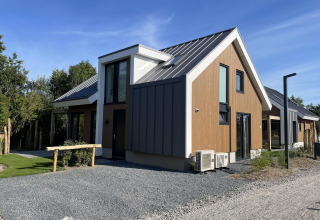 Moderno lodge 'Duinvilla' a EuroParcs Texel, Paesi Bassi, con facciata in legno e metallo sotto cielo azzurro.