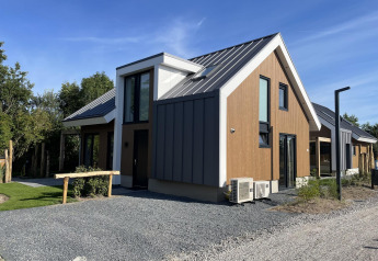 Moderno lodge 'Duinvilla' a EuroParcs Texel, Paesi Bassi, con facciata in legno e metallo sotto cielo azzurro.