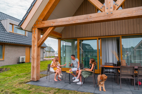 Gezin geniet op het terras bij EuroParcs Cadzand-Bad vakantiepark in Zeeland, Nederland, met hun hond.