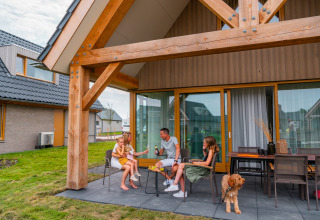 Familia disfrutando en la terraza de EuroParcs Cadzand-Bad, un parque vacacional en Zeeland, Países Bajos.