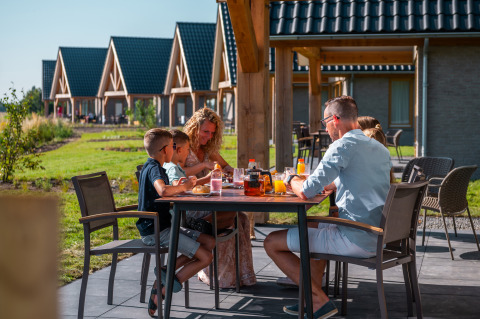 Gezin ontbijt buiten aan tafel bij EuroParcs Cadzand-Bad, een vakantiepark in Zeeland, Nederland.