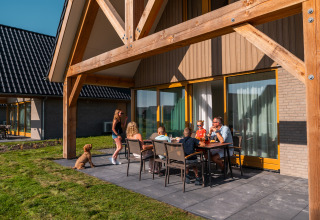 Famiglia che si gode un pasto all'aperto sul patio di una casa vacanze a EuroParcs Cadzand-Bad, Zelanda, Paesi Bassi.