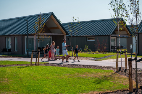 Famiglia passeggia davanti alle case vacanza di EuroParcs Cadzand-Bad, villaggio turistico in Zelanda, Paesi Bassi.