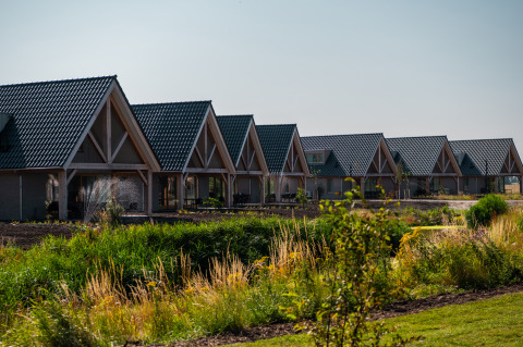 Row of holiday cottages with blue roofs at EuroParcs Cadzand-Bad park in Zeeland, Netherlands.