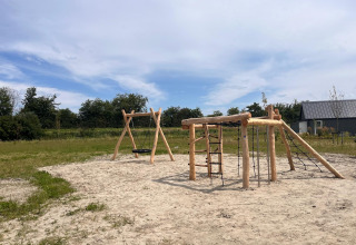 Speelplaats met houten schommels en klimrek bij EuroParcs Cadzand-Bad in Zeeland, Nederland.