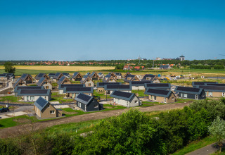 Vista di nuove case residenziali e campi rurali vicino a Cadzand, Zelanda, Paesi Bassi, sotto cielo azzurro.