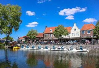 A view of pedal boats along a canal with traditional Dutch houses in Nieuwvliet, Zeeland, Netherlands.