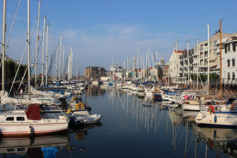 Sailboats and waterfront apartments by the canal near Nieuwvliet, Zeeland, Netherlands on a sunny day.