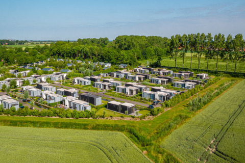 Luftaufnahme des Ferienparks EuroParcs Bad Meersee in Zeeland, Niederlande, mit modernen Chalets und viel Grün.