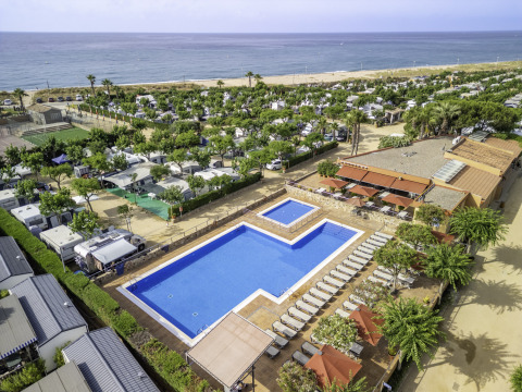 Aerial view of pool, sun loungers, mobile homes, and the beach at Campsite del Mar in Catalonia, Spain.