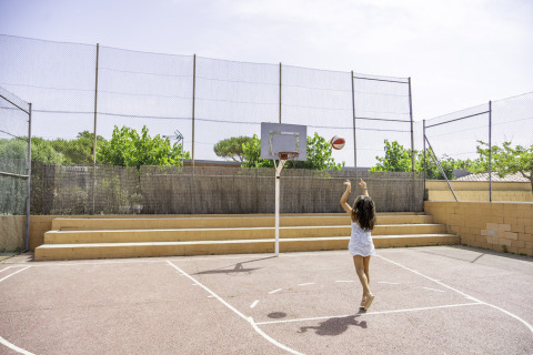 Een meisje gooit een basketbal op een buitenveld bij Campsite del Mar, een vakantiepark in Catalonië, Spanje.