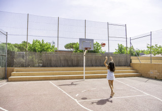 Ein Mädchen wirft einen Basketball auf einem Freiplatz im Campsite del Mar, einem Ferienpark in Katalonien, Spanien.