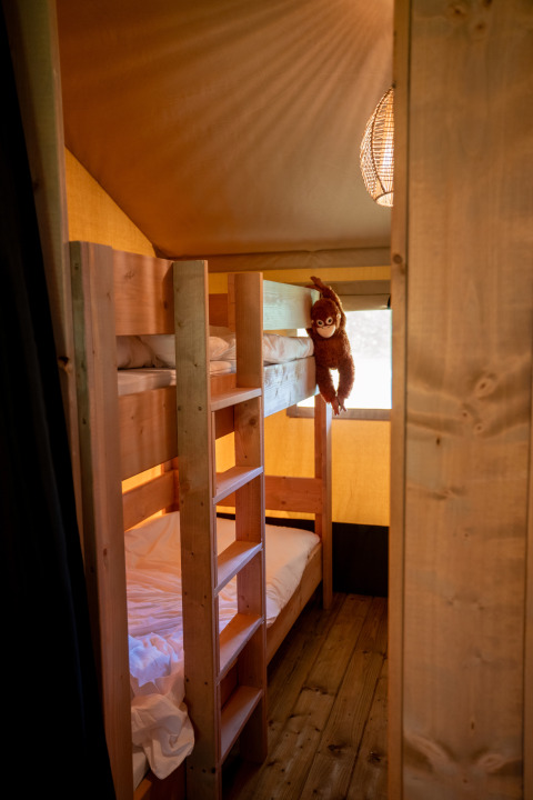 Innenansicht eines Safarizelts im Forest Lodge, Jocomo Parc, Belgien mit Etagenbetten und Affen-Plüschtier.