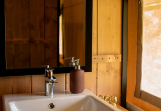 Rustikales Badezimmer mit Waschbecken und Spiegel im Safari-Zelt Forest Lodge, Jocomo Parc, Belgien.