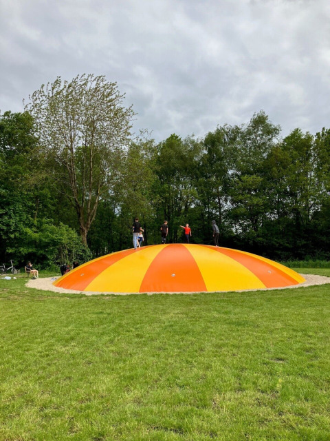 Children playing on a large orange and yellow inflatable pillow at Campsite de Bouwte in Groningen, Netherlands.