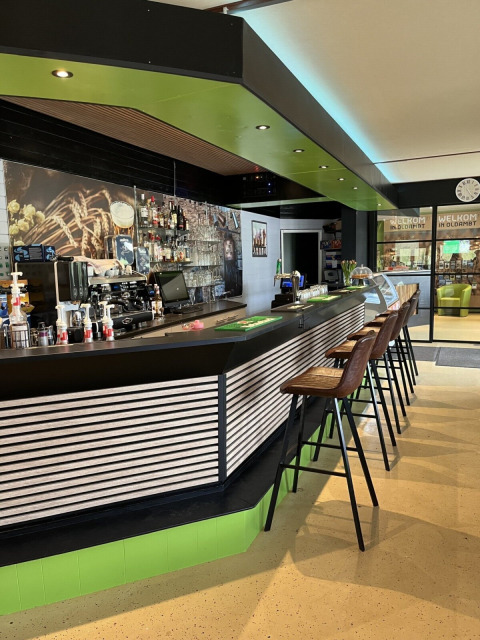 Zona bar moderna al Campeggio de Bouwte a Groningen, Paesi Bassi, con sgabelli e arredamento elegante.