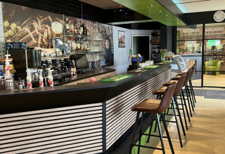 Modern bar area at Campsite de Bouwte in Groningen, Netherlands, featuring bar stools and sleek decor.