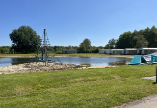 Campeggio de Bouwte a Groningen, Paesi Bassi, con laghetto, casette e giochi all'aperto in una giornata di sole.