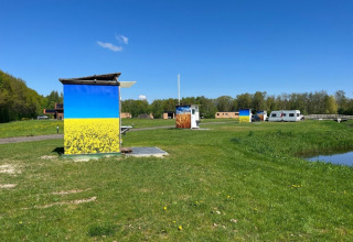 Campsite de Bouwte in Groningen, Netherlands, with painted huts, grassy field, and blue sky view.