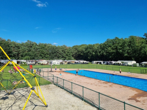 Outdoor swimming pool and playground at Campsite San Lanaco set in lush green Belgian Limburg scenery.