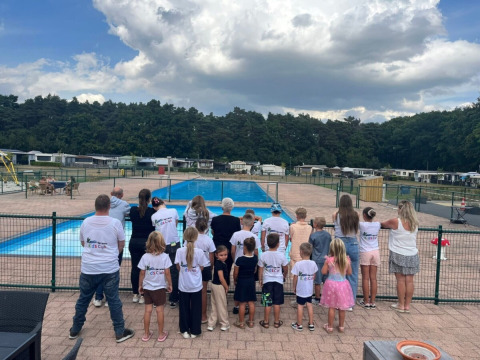 Gruppo di bambini e adulti vicino alla piscina al campeggio San Lanaco, Limburgo belga, in un giorno nuvoloso.