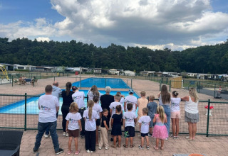 Gruppo di bambini e adulti vicino alla piscina al campeggio San Lanaco, Limburgo belga, in un giorno nuvoloso.