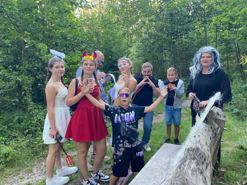 Bambini e adulti in costume festeggiano al campeggio San Lanaco nel Limburgo belga, circondati dal bosco.