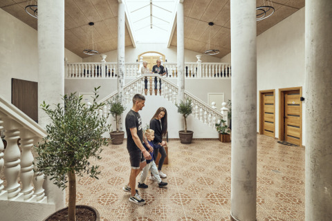 Family walking through bright lobby with columns and stairs at Emmerbølle Strand Camping, Southern Denmark.