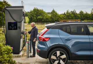 Mann lädt sein Elektroauto an einer Ladestation bei Emmerbølle Strand Camping im Süden Dänemarks auf.
