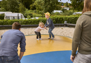 Bambini che giocano e saltano su un tappeto elastico gonfiabile a Emmerbølle Strand Camping, Sud della Danimarca.