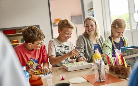 Kinder und Jugendliche basteln und malen gemeinsam im Aufenthaltsraum von Emmerbølle Strand Camping.