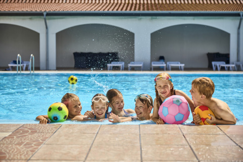 Kinderen spelen vrolijk met kleurrijke ballen in het zwembad bij Emmerbølle Strand Camping in Zuid-Denemarken.