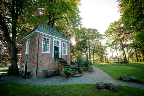Gezellige glamping-accommodatie met een bakstenen huisje, omgeven door bomen en een groene grasmat.